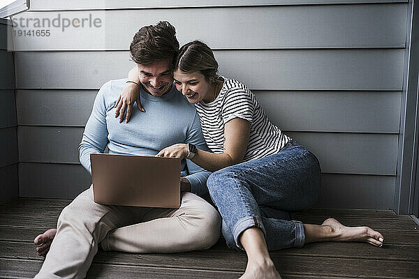 Glückliches junges Paar  das zusammen Laptop benutzt