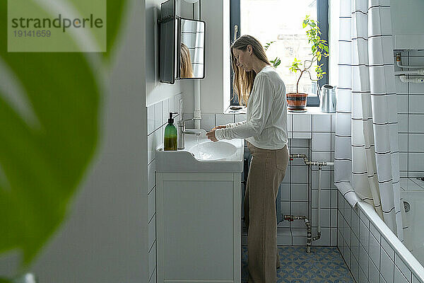 Woman washing hands in bathroom at home