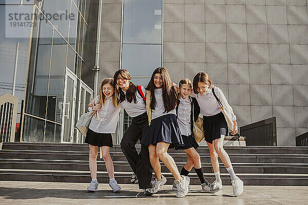 Fröhliche Schulmädchen tanzen vor dem Schulgebäude