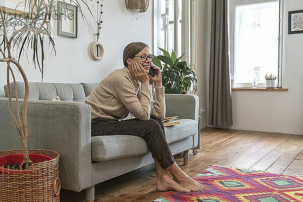 Glückliche Frau  die zu Hause mit dem Handy telefoniert