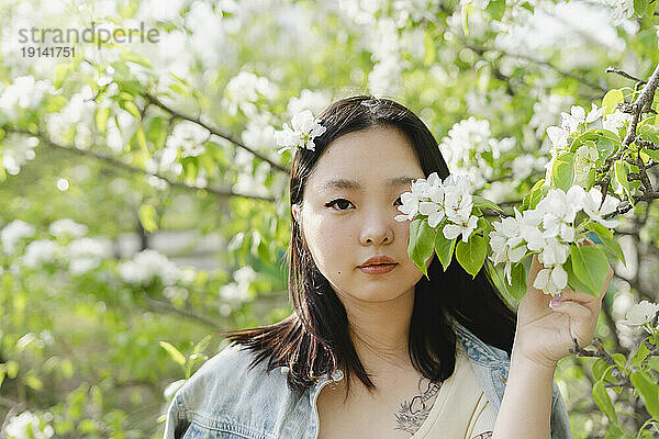 Junge Frau hält einen Zweig mit weißen Blüten