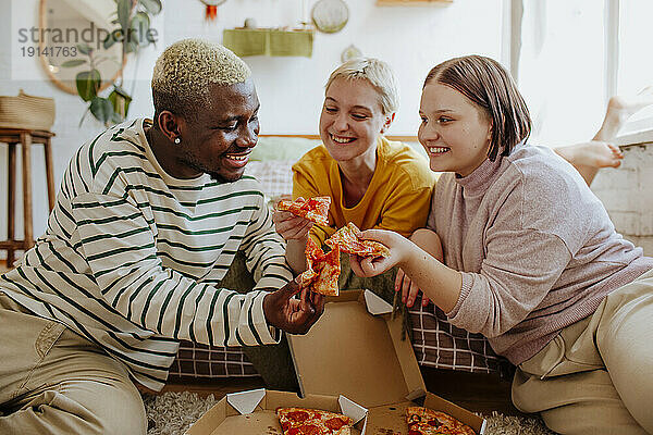 Glückliche junge Freunde  die zu Hause Pizza essen