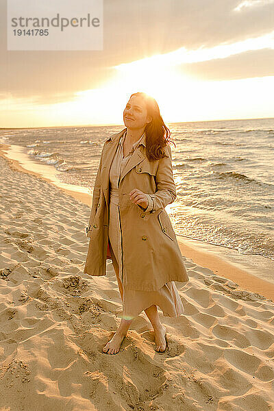 Lächelnde Frau steht am Strand