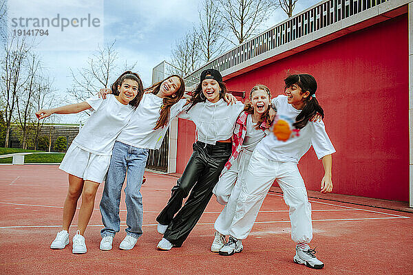 Verspielte Teenager-Mädchen mit Armen an der Wand auf dem Spielplatz