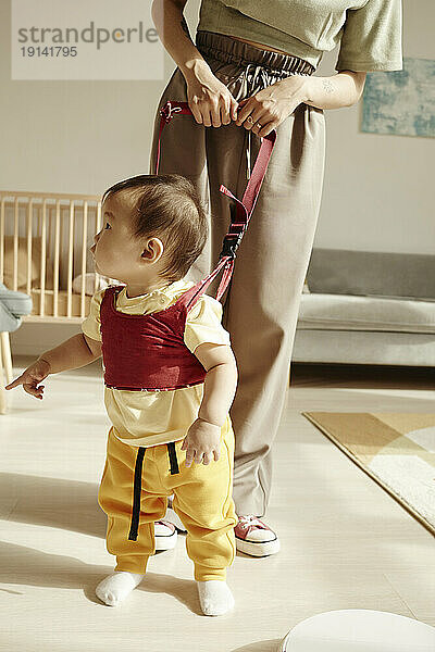 Mother supporting daughter learning to walk at home