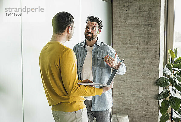 Geschäftsmann diskutiert mit Kollegen  der im Büro lehnt