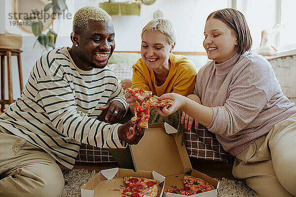 Fröhliche junge Freunde genießen Pizza im Bett