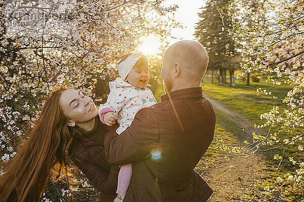 Familie spielt mit Tochter im Park an einem sonnigen Tag