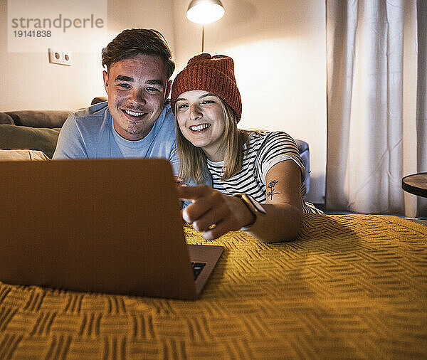 Happy young couple using laptop together at home