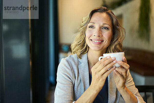 Nachdenkliche Geschäftsfrau träumt davon  Tasse im Café zu halten