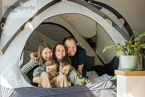 Glückliche Familie mit Vizsla-Hund im Zelt zu Hause