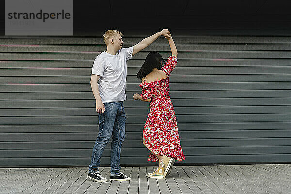 Young couple dancing in front of closed shutter