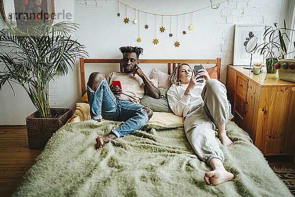 Paar nutzt Smartphones und entspannt sich zu Hause im Bett