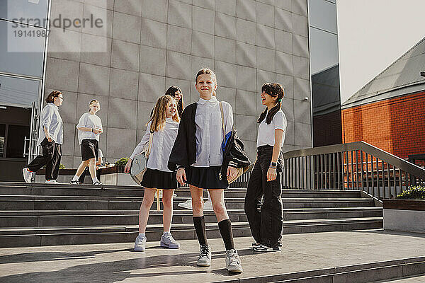 Schoolgirls standing by steps in front of school building