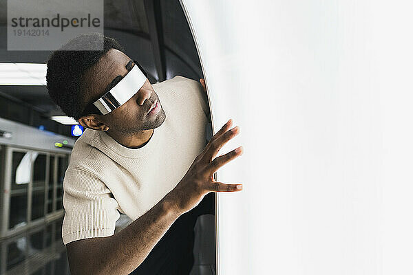 Futuristic man with cyber glasses examining light pane