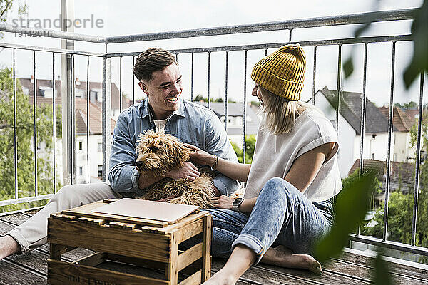 Glückliches Paar  das Spaß mit Hund auf dem Balkon hat
