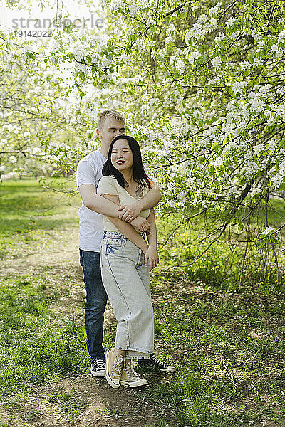 Junges Paar umarmt sich am Baum im Park