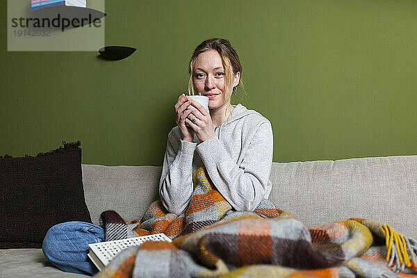Young woman holding mug relaxing on couch