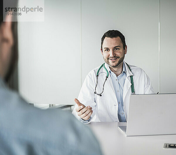 Lächelnder Arzt erklärt Patient in der Klinik