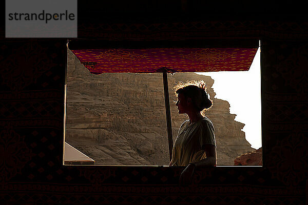 Frau steht bei Sonnenuntergang im Wüstenlager am Zelt