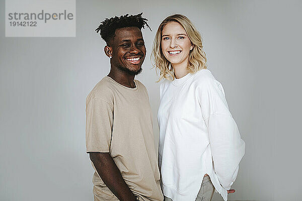 Smiling young couple standing against gray background