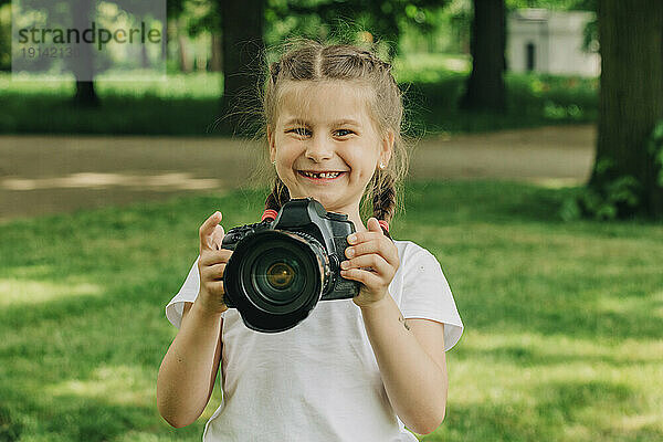 Fröhliches Mädchen mit Kamera im Park
