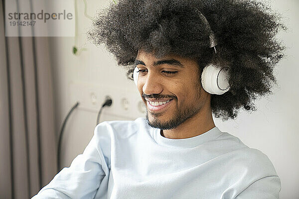 Lächelnder Freiberufler mit Bluetooth-Kopfhörern zu Hause