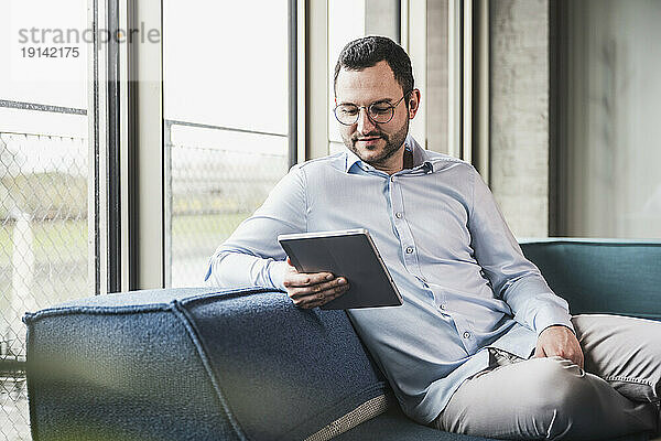 Geschäftsmann sitzt mit Tablet-PC auf der Couch im Büro