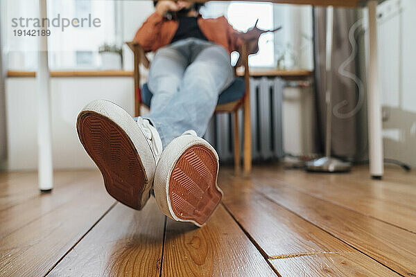 Young man with legs crossed over hardwood floor at home