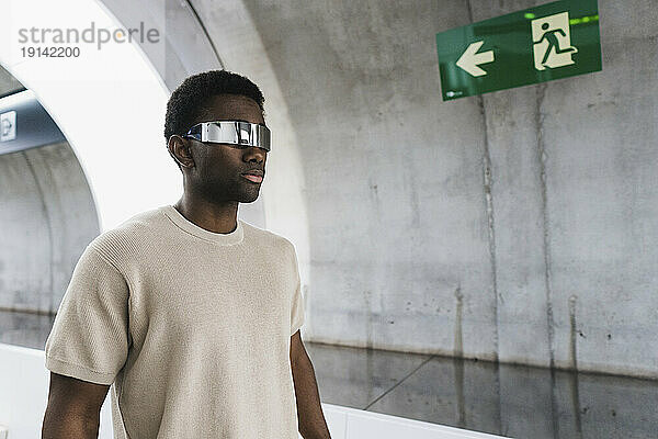 Junger Mann trägt eine Cayber-Brille und läuft durch den U-Bahn-Tunnel