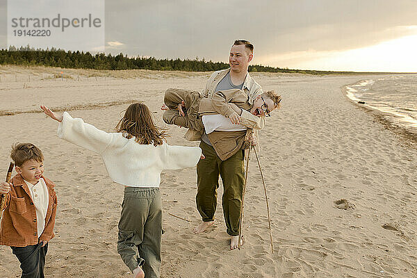 Vater hat Spaß mit Tochter und Söhnen am Strand