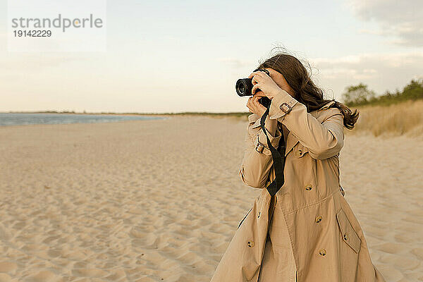 Frau fotografiert mit Kamera am Strand