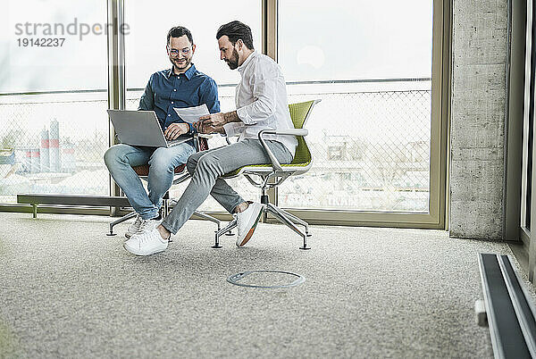 Geschäftskollegen diskutieren am Laptop am Glasfenster