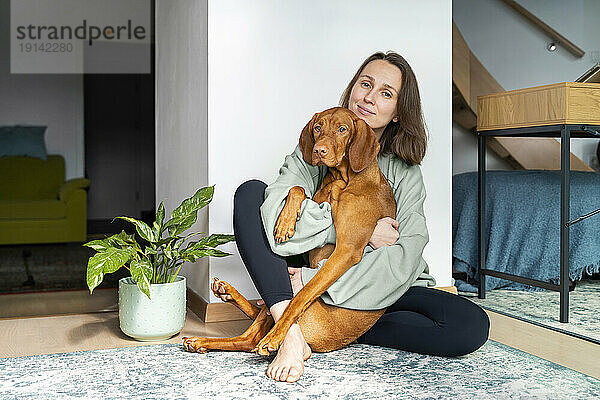 Woman embracing Vizsla dog at home