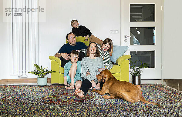 Familie mit Vizsla-Hund entspannt sich im heimischen Wohnzimmer