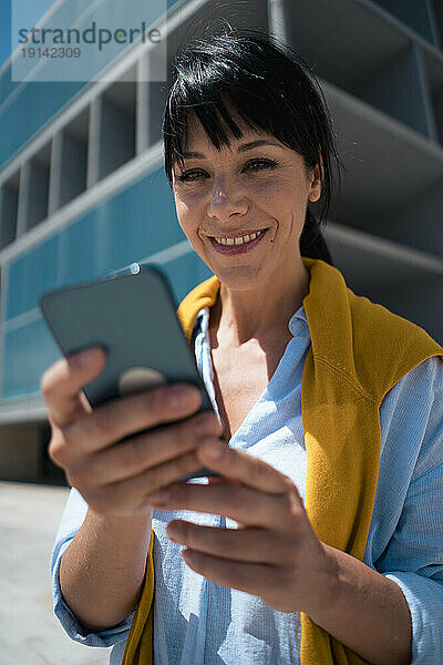 Lächelnde reife Geschäftsfrau mit Mobiltelefon