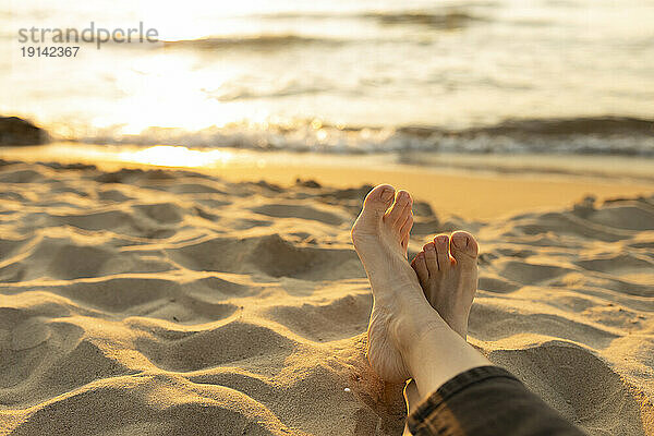 Frau entspannt sich barfuß im Sand am Strand