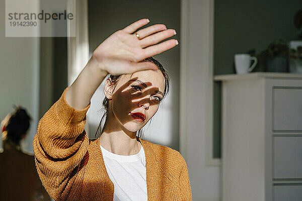 Frau schützt ihre Augen zu Hause vor Sonnenlicht
