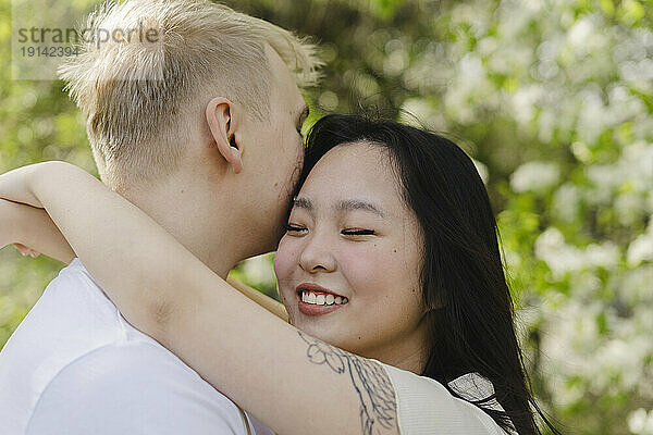 Smiling young woman embracing boyfriend at park