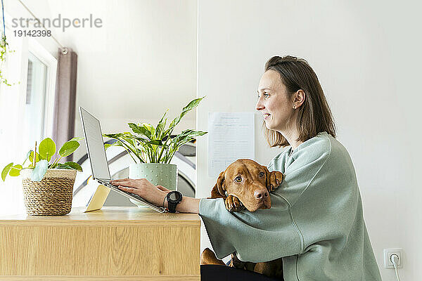 Freiberufler arbeitet zu Hause am Laptop mit Hund