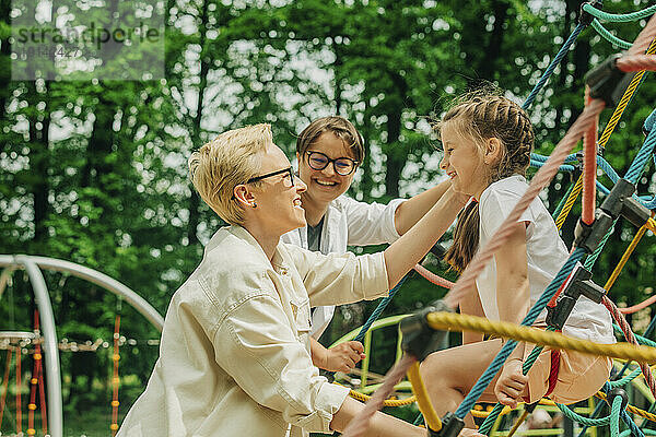 Cheerful lesbian mothers enjoying with daughter at playground
