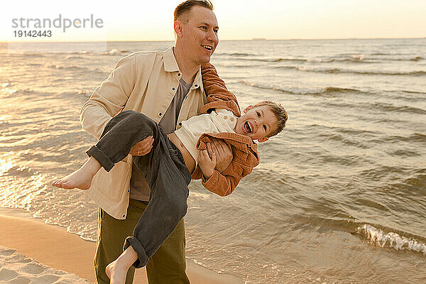 Glücklicher Vater  der Spaß mit Sohn am Strand hat