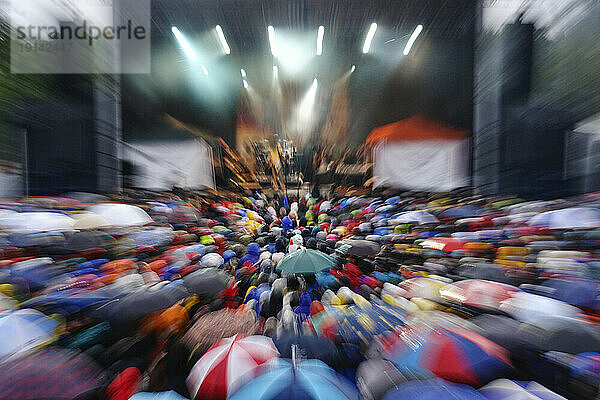 Crowded music festival with fans carrying umbrellas