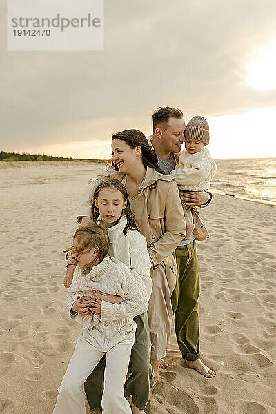 Glückliche Frau steht mit ihrer Familie am Strand