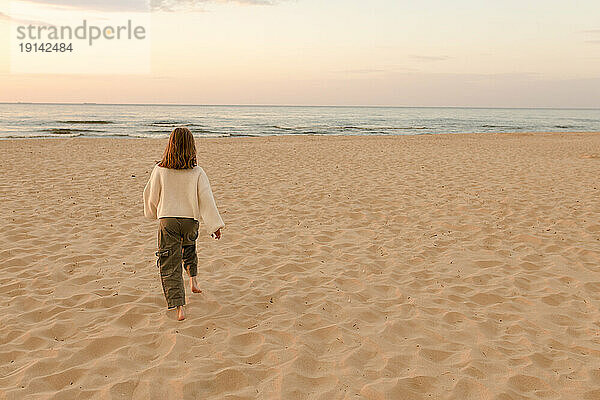 Mädchen läuft am Strand auf Sand