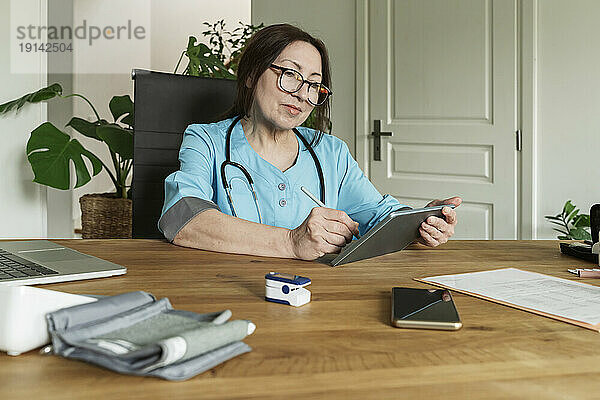 Reifer Arzt nutzt Tablet-PC in der Arztpraxis