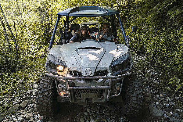 Junge lächelnde Freunde fahren Buggy im Wald