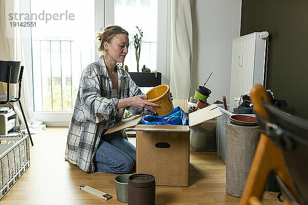 Junge Frau packt zu Hause Behälter aus Karton aus