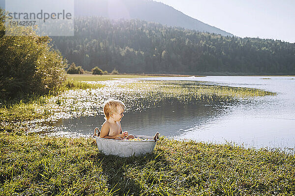 Happy girl taking bath in tub by lake