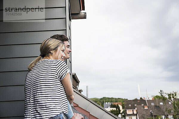Lächelnder Mann und Frau stehen zusammen auf dem Balkon